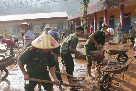 Các chiến sỹ Công an chung tay khắc phục hậu quả mưa lũ tại Trường PTDT Bán trú tiểu học Chà Nưa. (Ảnh: Xuân Tư/TTXVN)