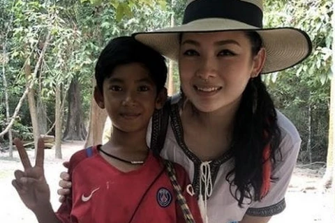 Cậu bé Campuchia chụp ảnh cùng nữ du khách. (Nguồn: nextshark.com)
