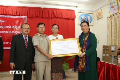 Phó Chủ tịch Thường trực Quốc hội Tòng Thị Phóng trao tặng quà cho Trường PTTH Hữu nghị Việt Nam-Lào. (Ảnh: Xuân Tú/TTXVN)