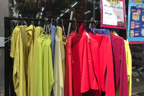 Để đối phó với thời tiết 'nắng như đổ lửa', người tiêu dùng Thủ đô phải săn tìm những phụ kiện như áo chống nắng. (Ảnh: Việt Anh/Vietnam+)