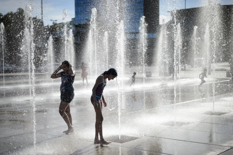 Người dân Thụy Sĩ tránh nóng bên vòi phun nước. (Ảnh: AFP/TTXVN)