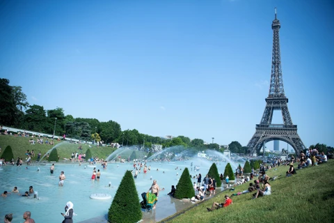 Người dân tại Paris (Pháp) tránh nóng tại các vòi phun nước ở gần tháp Eiffel. (Ảnh: THX/TTXVN)
