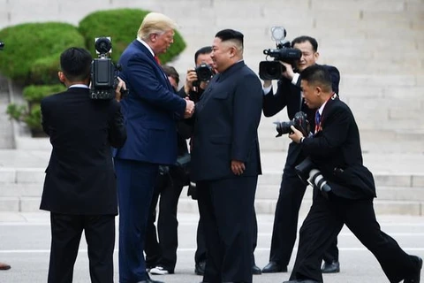 Tổng thống Mỹ Donald Trump (giữa, trái) bắt tay nhà lãnh đạo Triều Tiên Kim Jong-un (giữa, phải) tại Khu phi quân sự (DMZ) ở biên giới liên Triều chiều 30/6/2019.(Ảnh: AFP/TTXVN)