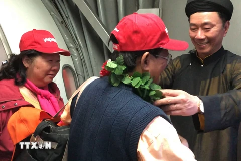 Đại sứ Việt Nam tại Ấn Độ Phạm Sanh Châu tặng vòng hoa chào đón hành khách Việt Nam trên chuyến bay VJ971. (Ảnh: Huy Lê/Vietnam+) 