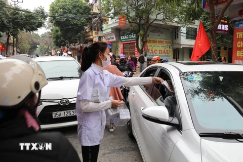Nhân viên một cửa hàng thuốc tại Ninh Bình phát khẩu trang y tế miễn phí cho người dân. (Ảnh: Đức Phương/TTXVN)