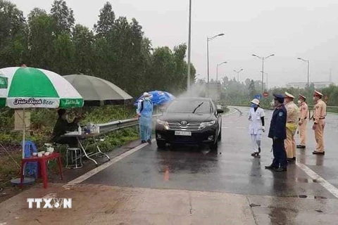 Phun khử khuẩn đối với xe ôtô ra vào tỉnh ở đường nhánh rẽ vào cao tốc Nội Bài-Lào Cai. (Ảnh: Nguyễn Thảo/TTXVN)