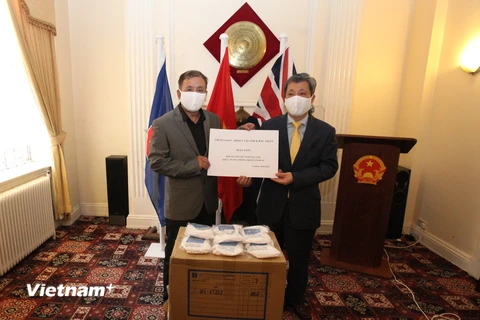 Đại sứ Trần Ngọc An trao khẩu trang kháng khuẩn cho đại diện Hội người Việt Nam tại Anh. (Ảnh: Đình Thư/Vietnam+) 