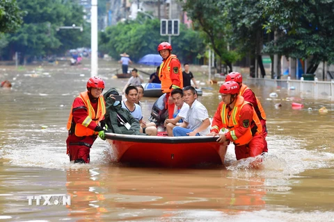 Lực lượng cứu hộ sơ tán người dân khỏi vùng ngập lụt. (Ảnh: THX/ TTXVN)