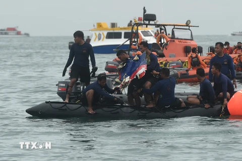 Lực lượng cứu hộ tìm kiếm mảnh vỡ máy bay. (Ảnh: AFP/TTXVN)