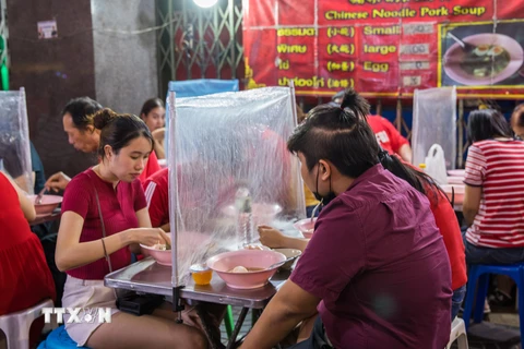 Một quán ăn ở Bangkok sử dụng tấm chắn để ngăn dịch bệnh lây lan. (Ảnh: AFP/TTXVN)