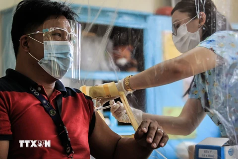 Tiêm vaccine ngừa COVID-19 cho một nhân viên tế tại Manila. (Ảnh: THX/TTXVN)