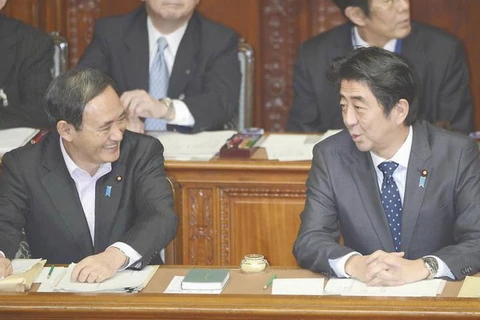 Thủ tướng Nhật Bản Shinzo Abe (P) trao đổi với Chánh Văn phòng Nội các Yoshihide Suga trong phiên họp tại Hạ viện. (Ảnh: Kyodo)