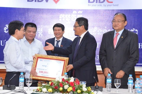 Đại diện BIDV trao trượng trưng 100.000 USD cho Bộ trưởng Sok Chenda. (Ảnh: Chí Hùng/Vietnam+)
