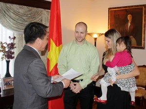 Đại sứ Việt Nam tại Canada Lê Sỹ Vương Hà trao quyết định về việc nhận con nuôi Việt Nam cho một gia đình ở Canada. (Ảnh: Thanh Hải/Vietnam+)