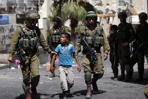 Binh sỹ Israel bắt giữ một cậu bé người Palestine tại khu vực Bờ Tây. (Ảnh: AFP)