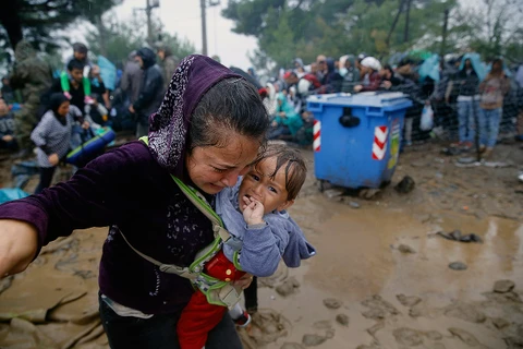 Hàng nghìn người di cư, trong đó có nhiều trẻ nhỏ, bị ướt sũng khi phải dầm mình dưới mưa xối xả tại biên giới Hy Lạp-Macedonia. (Ảnh: AFP)