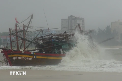 Một tàu cá bị mắc cạn, có nguy cơ bị sóng đánh chìm tại cửa biển Nhật Lệ, thành phố Đồng Hới, tỉnh Quảng Bình. (Ảnh: TTXVN)