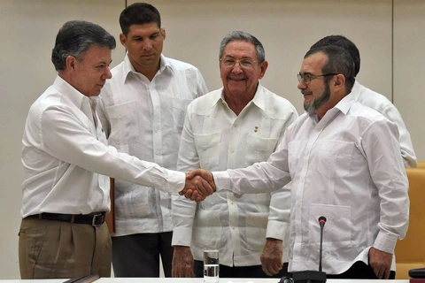Tổng thống Colombia Juan Manuel Santos (trái) bắt tay thủ lĩnh FARC Timochenko (phải) dưới sự chứng kiến của Chủ tịch Cuba Raul Castro tại vòng đàm phán hòa bình ở Cuba. (Ảnh: AFP) 