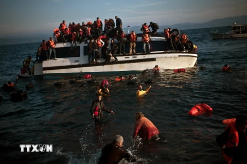 Lực lượng cứu hộ hỗ trợ người di cư rời khỏi chiếc tàu bị chìm ngoài khơi đảo Lesbos. (Ảnh: AFP/TTXVN)