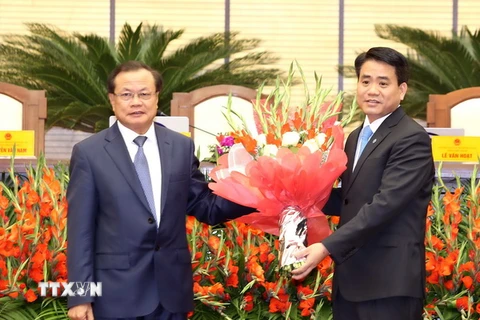 Ông Phạm Quang Nghị, Ủy viên Bộ Chính trị, chỉ đạo Thành ủy Hà Nội tặng hoa chúc mừng tân Chủ tịch ​UBND thành phố Hà Nội Nguyễn Đức Chung. (Ảnh: TTXVN)