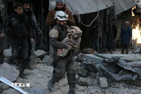 Nhân viên dân sự Syria chuyển một em nhỏ bị thương trong các cuộc giao tranh giữa quân đội chính phủ và phiến quân IS. (Ảnh: AFP/TTXVN)