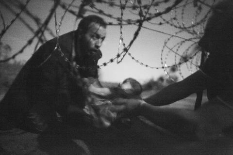 Bức ảnh đoạt giải Bức ảnh của năm trong cuộc thi World Press Photo 2016 chụp cảnh một người đàn ông tị nạn chuyển một đứa bé qua hàng rào thép gai tại biên giới Hungary-Serbia. (Nguồn: worldpressphoto.org)