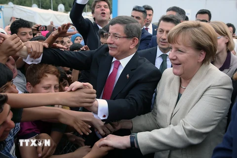Thủ tướng Đức Angela Merkel (phải) và Thủ tướng Thổ Nhĩ Kỳ Ahmet Davutoglu gặp gỡ những người tị nạn trong chuyến thăm Gaziantep. (Nguồn: THX/TTXVN)