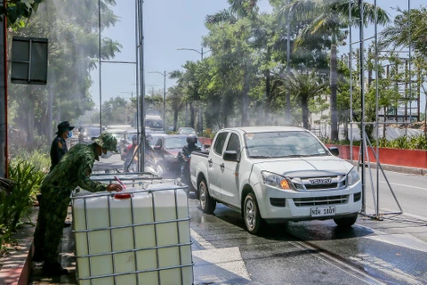 Các phương tiện được phun khử khuẩn trước khi di chuyển vào thủ đô Manila, Philippines ngày 23/3/2020. (Ảnh: THX/TTXVN)