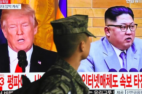 Một binh sỹ Hàn Quốc đi ngang qua màn hình chiếu hình Tổng thống Donald Trump và nhà lãnh đạo Triều Tiên Kim Jong Un. (Ảnh: AFP)