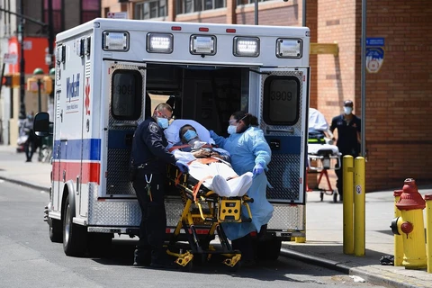 Nhân viên y tế chuyển nạn nhân nhiễm COVID-19 tới bệnh viện ở Brooklyn, New York, Mỹ. (Ảnh: AFP/TTXVN)