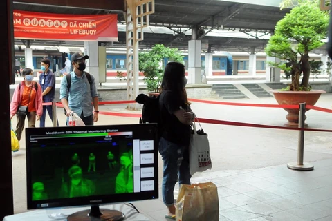 Hành khách đi qua máy kiểm tra thân nhiệt tại ga Sài Gòn. (Ảnh: Tiến Lực/TTXVN)