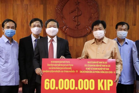 Ông Bounkong Syhavong (phải), Bộ trưởng Bộ Y tế, Phó Trưởng Ban chỉ đạo quốc gia về phòng chống dịch Covid -19 Lào tiếp nhận ủng hộ. (Ảnh: Phạm Kiên/TTXVN)