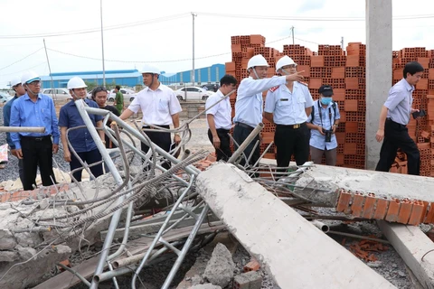 Thứ trưởng Lê Quang Hùng cùng đoàn công tác liên bộ kiểm tra hiện trường sập công trình xây dựng. (Ảnh: Sỹ Tuyên/TTXVN)