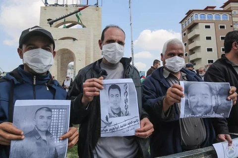 Người dân Palestine cầm bức ảnh của các tù nhân bị Israel bắt giữ. (Nguồn: AFP)