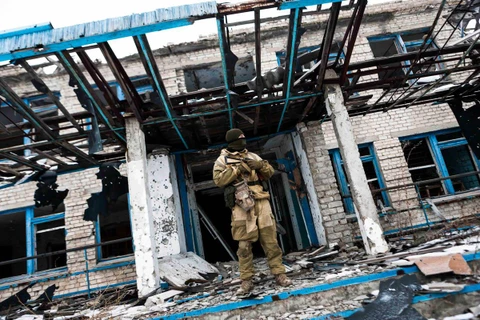 Binh sỹ Ukraine đứng trước một ngôi trường bị phá hủy tại thành phố Mariupol thuộc tỉnh Donetsk. (Nguồn: Aljazeera)