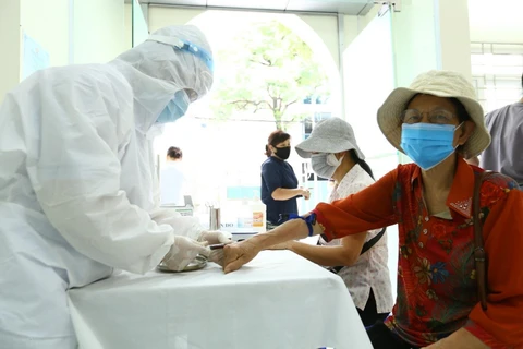Nhân viên y tế lấy mẫu xét nghiệm nhanh cho người về từ Đà Nẵng. (Ảnh: Minh Quyết/TTXVN)
