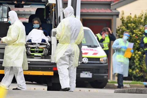 Nhân viên y tế chuyển bệnh nhân nghi mắc COVID-19 lên xe cứu thương tại bang Victoria, Australia ngày 27/7/2020. (Ảnh: AFP/TTXVN)