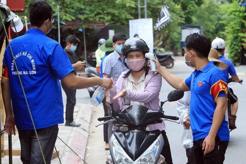 Lực lượng đoàn thanh niên quận Đồ Sơn, Hải Phòng kiểm tra thân nhiệt, phun dung dịch sát khuẩn tay tại chốt kiểm soát dịch COVID-19. (Ảnh: An Đăng/TTXVN)