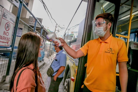 Người dân được kiểm tra thân nhiệt phòng lây nhiễm COVID-19 trước khi lên xe buýt tại Manila, Philippines, ngày 19/8/2020. (Ảnh: THX/TTXVN)