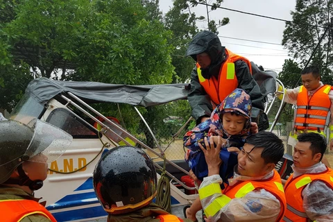 Di chuyển người dân ra khỏi khu vực ngập lũ tại huyện Cam Lộ. (Ảnh: Thanh Thủy/TTXVN)
