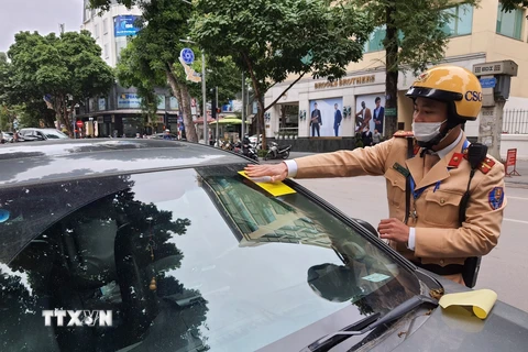 Cảnh sát giao thông dán phạt nguội đối với phương tiện dừng, đỗ trái phép trên phố Bà Triệu. (Ảnh: Doãn Tấn/TTXVN)