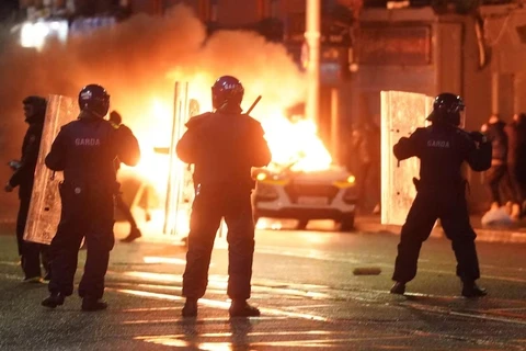 Cảnh sát Ireland đứng tại hiện trường một vụ tấn công, gây rối trật tự công cộng ở Dublin tối 23/11. (Ảnh: AP)