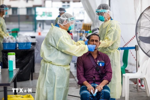 Nhân viên y tế lấy mẫu xét nghiệm COVID-19 cho người dân tại Singapore. (Ảnh: AFP/TTXVN)