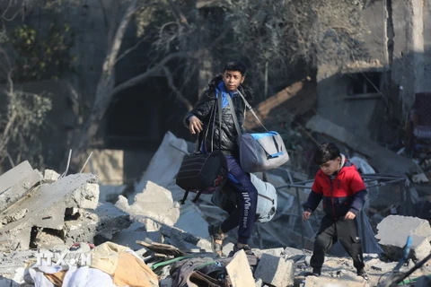 Người dân nhặt nhạnh đồ đạc còn sót lại trong đống đổ nát sau vụ không kích của Israel xuống trại tị nạn Al-Maghazi ở Dải Gaza ngày 31/12/2023. (Ảnh: THX/TTXVN)