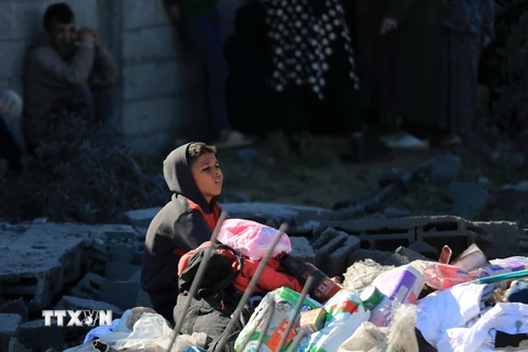 Một em nhỏ Palestine ngồi giữa đống đổ nát sau cuộc oanh kích của Israel xuống thành phố Rafah, Dải Gaza, ngày 7/1/2024. (Ảnh: THX/TTXVN)