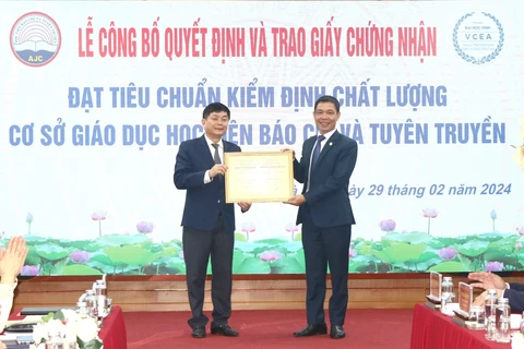 Tiến sỹ Nguyễn Đình Huy, Phó Giám đốc Trung tâm Kiểm định Chất lượng Giáo dục-Trường Đại học Vinh trao Giấy chứng nhận đạt tiêu chuẩn chất lượng cơ sở giáo dục cho Học viện Báo chí và Tuyên truyền. (Ảnh: Lê Hằng-Minh Trang/Vietnam+)