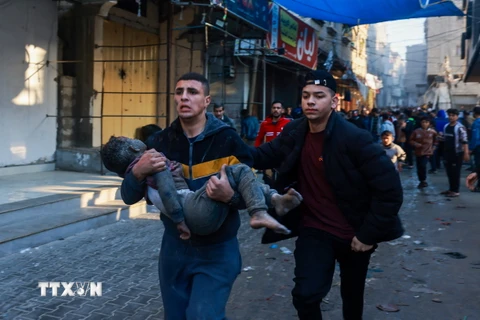 Chuyển em nhỏ bị thương sau cuộc oanh tạc của Israel xuống thành phố Rafah, Dải Gaza ngày 1/12/2023. (Ảnh: AFP/TTXVN)