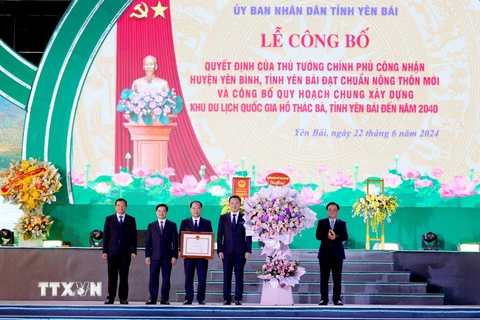 Bộ trưởng Bộ Nông nghiệp và Phát triển Nông thôn Lê Minh Hoan trao bằng công nhận huyện đạt chuẩn nông thôn mới và tặng hoa chúc mừng Đảng bộ, chính quyền và nhân dân các dân tộc huyện Yên Bình. (Ảnh: Tuấn Anh/TTXVN)