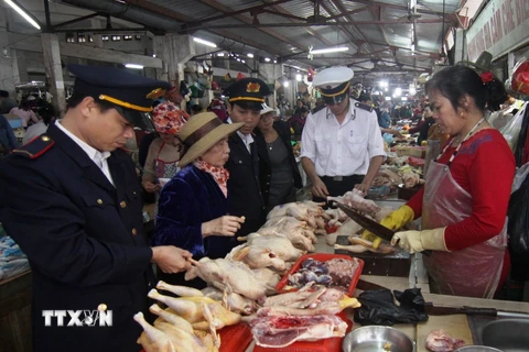 Nhân viên Chi cục Thú y kiểm tra cơ sở kinh doanh thịt gia cầm tại chợ. (Ảnh: Vũ Sinh/TTXVN)