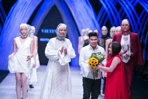 Nhà thiết kế Quang Việt nhận hoa chúc mừng từ ban tổ chức cho lần trở về quê nhà này. (Ảnh: BTC)